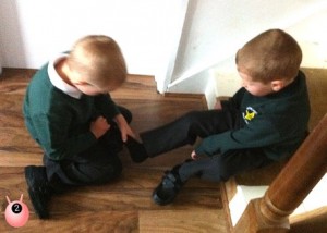 Brother helping his younger brother put his shoes on for his first day of school