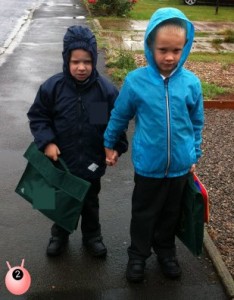 Brothers holding hands walking together in the rain on the school run